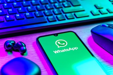 Prague, Czechia - 08 12 2025: A side view of a desk with a keyboard and a mobile phone displaying the WhatsApp logo. WhatsApp is an app for sending texts, calls, and media.