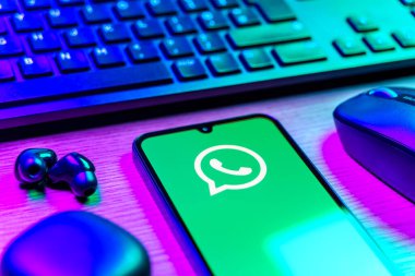 Prague, Czechia - 08 12 2025: A side view of a desk with a keyboard and a mobile phone displaying the WhatsApp logo. WhatsApp is an app for sending texts, calls, and media.