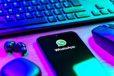 Prague, Czechia - 08 12 2025: A side view of a desk with a keyboard and a mobile phone displaying the WhatsApp logo. WhatsApp is an app for sending texts, calls, and media.
