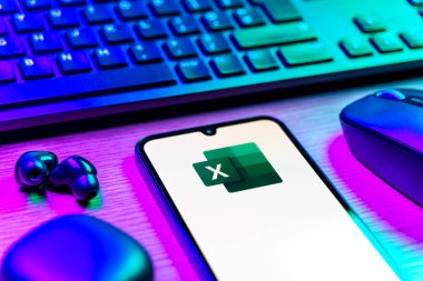 Prague, Czechia - 08 12 2025: A side view of a desk with a keyboard and a mobile phone displaying the Excel logo. Excel is a software for spreadsheets, data analysis, and calculations.