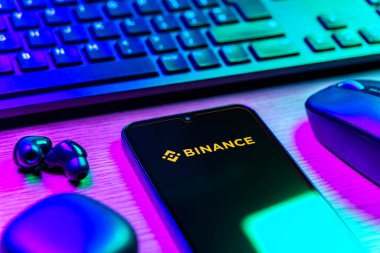 Prague, Czechia - 08 12 2025: A side view of a desk with a keyboard and a mobile phone displaying the Binance logo. Binance is a cryptocurrency exchange for trading digital assets.