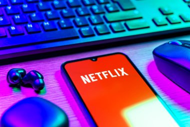 Prague, Czechia - 08 12 2025: A side view of a desk with a keyboard and a mobile phone displaying the Netflix logo. Netflix is a streaming platform for movies and TV shows.