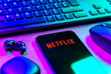 Prague, Czechia - 08 12 2025: A side view of a desk with a keyboard and a mobile phone displaying the Netflix logo. Netflix is a streaming platform for movies and TV shows.