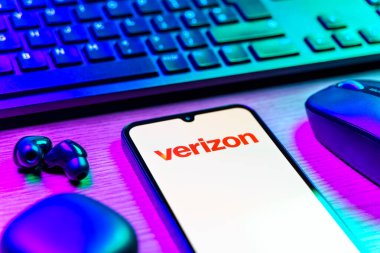 Prag, Çek Cumhuriyeti - 08 12 2025: Verizon logosunu gösteren klavyeli ve cep telefonlu bir masanın yan görüntüsü. Verizon, kablosuz ve geniş bant hizmetleri sağlayan bir telekom şirketidir..