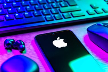 Prag, Çek Cumhuriyeti - 08 12 2025: Apple logosunu gösteren klavyesi ve cep telefonu olan bir masanın yan görüntüsü. Apple iPhone, bilgisayar ve hizmet üreten bir teknoloji şirketidir..