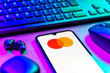Prag, Çek Cumhuriyeti - 08 12 2025: Mastercard logosunu gösteren klavyesi ve cep telefonu olan bir masanın yan görüntüsü. Mastercard ödeme kartları ve hizmetler sağlayan bir finans şirketidir..