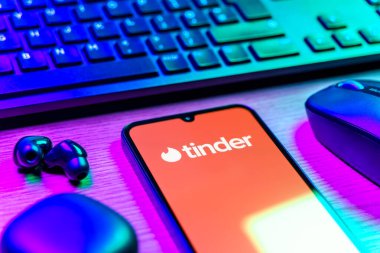 Prag, Çek Cumhuriyeti - 08 12 2025: Tinder logosunu gösteren klavyesi ve cep telefonu olan bir masanın yan görüntüsü. Tinder insanları eşleştirmek ve bağlamak için bir randevu uygulaması.