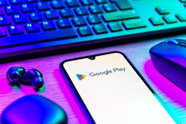 Prag, Çek Cumhuriyeti - 08 12 2025: Google Play logosunu gösteren klavyesi ve cep telefonu olan bir masanın yan görüntüsü. Google Play uygulamaları, oyunları ve dijital içeriği indirmek için bir platformdur.