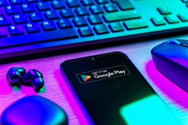 Prag, Çek Cumhuriyeti - 08 12 2025: Google Play logosunu gösteren klavyesi ve cep telefonu olan bir masanın yan görüntüsü. Google Play uygulamaları, oyunları ve dijital içeriği indirmek için bir platformdur.