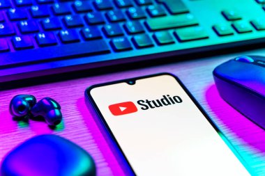 Prag, Çek Cumhuriyeti - 08 12 2025: Youtube Stüdyo logosunu gösteren klavyesi ve cep telefonu olan bir masanın yan görüntüsü. Youtube Studio YouTube kanallarını yönetmek ve analiz etmek için bir platformdur.