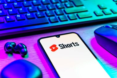 Prag, Çek Cumhuriyeti - 08 12 2025: Youtube Shorts logosunu gösteren klavyesi ve cep telefonu olan bir masanın yan görüntüsü. Youtube Shorts kısa form video içeriği için bir platformdur.