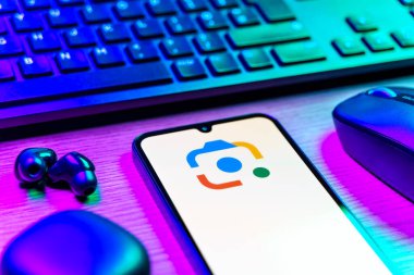 Prag, Çek Cumhuriyeti - 08 12 2025: Google Lens logosunu gösteren klavyesi ve cep telefonu olan bir masanın yan görüntüsü. Google Lens, resimlerdeki görsel arama ve bilgi için kullanılan bir araçtır..