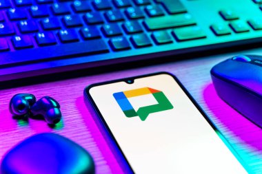 Prag, Çek Cumhuriyeti - 08 12 2025: Google Chat logosunu gösteren klavyesi ve cep telefonu olan bir masanın yan görüntüsü. Google Chat mesajlaşma ve takım işbirliği için bir platformdur.