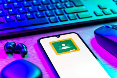 Prag, Çek Cumhuriyeti - 08 12 2025: Google Sınıfı logosunu gösteren klavyesi ve cep telefonu olan bir masanın yan görüntüsü. Google Sınıfı, sınıfları ve eğitim içeriğini yönetmek için bir platformdur.