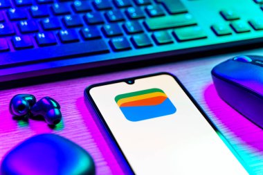 Prag, Çek Cumhuriyeti - 08 12 2025: Google Cüzdan logosunu gösteren klavyesi ve cep telefonu olan bir masanın yan görüntüsü. Google Cüzdanı dijital ödeme yöntemlerini depolamak ve kullanmak için bir platformdur.