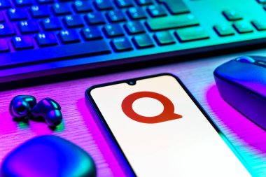 Prag, Çek Cumhuriyeti - 08 12 2025: Quora logosunu gösteren klavyesi ve cep telefonu olan bir masanın yan görüntüsü. Quora soru sormak ve bilgi paylaşmak için bir platformdur..