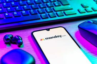 Prag, Çek Cumhuriyeti - 08 12 2025: Monday.com logosunu gösteren klavyesi ve cep telefonu olan bir masanın yan görüntüsü. Monday.com proje yönetimi ve takım işbirliği için bir platformdur.