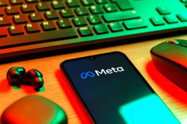 Prague, Czechia - 08 12 2025: A side view of a desk with a keyboard and a mobile phone displaying the Meta logo. Meta is a company offering social platforms like Facebook and Instagram.