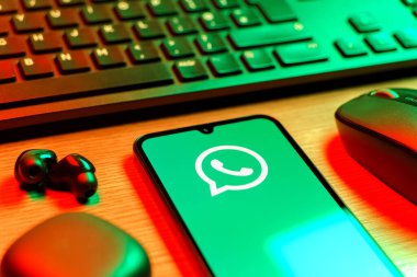 Prague, Czechia - 08 12 2025: A side view of a desk with a keyboard and a mobile phone displaying the WhatsApp logo. WhatsApp is an app for sending texts, calls, and media.