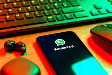 Prague, Czechia - 08 12 2025: A side view of a desk with a keyboard and a mobile phone displaying the WhatsApp logo. WhatsApp is an app for sending texts, calls, and media.
