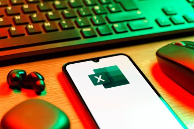 Prague, Czechia - 08 12 2025: A side view of a desk with a keyboard and a mobile phone displaying the Excel logo. Excel is a software for spreadsheets, data analysis, and calculations.