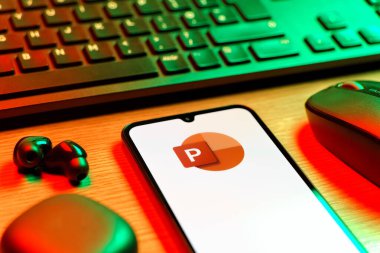 Prague, Czechia - 08 12 2025: A side view of a desk with a keyboard and a mobile phone displaying the Powerpoint logo. Powerpoint is a software for creating presentations and slideshows.