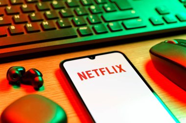 Prague, Czechia - 08 12 2025: A side view of a desk with a keyboard and a mobile phone displaying the Netflix logo. Netflix is a streaming platform for movies and TV shows.