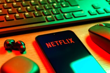 Prague, Czechia - 08 12 2025: A side view of a desk with a keyboard and a mobile phone displaying the Netflix logo. Netflix is a streaming platform for movies and TV shows.