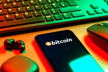 Prag, Çek Cumhuriyeti - 08 12 2025: Bitcoin logosunu gösteren klavyesi ve cep telefonu olan bir masanın yan görüntüsü. Bitcoin merkezi olmayan işlemler için dijital bir kripto para birimidir.