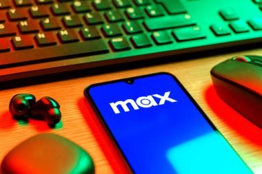 Prag, Çek Cumhuriyeti - 08 12 2025: Max logosunu gösteren klavyesi ve cep telefonu olan bir masanın yan görüntüsü. Max, filmler, TV programları ve özgün içerikler için bir yayın platformudur..