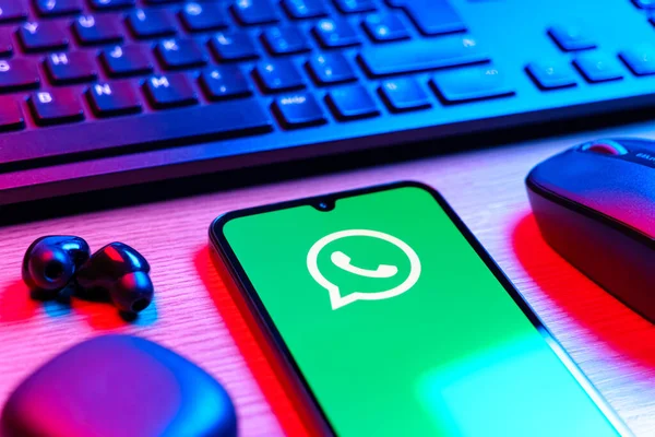 Prague, Czechia - 08 12 2025: A side view of a desk with a keyboard and a mobile phone displaying the WhatsApp logo. WhatsApp is an app for sending texts, calls, and media.