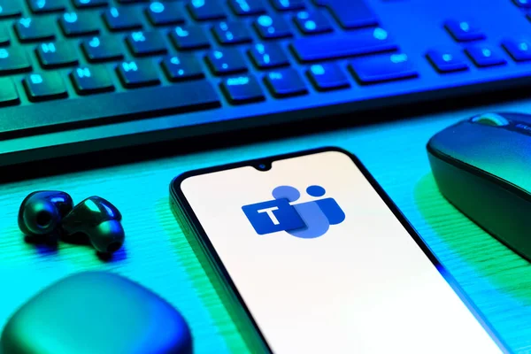 Prague, Czechia - 08 12 2025: A side view of a desk with a keyboard and a mobile phone displaying the Teams logo. Teams is a platform for team collaboration, meetings, and communication.