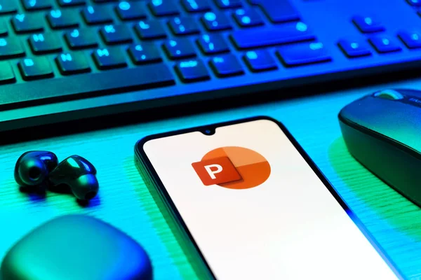 Prague, Czechia - 08 12 2025: A side view of a desk with a keyboard and a mobile phone displaying the Powerpoint logo. Powerpoint is a software for creating presentations and slideshows.