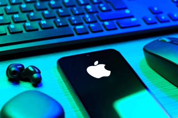 Prag, Çek Cumhuriyeti - 08 12 2025: Apple logosunu gösteren klavyesi ve cep telefonu olan bir masanın yan görüntüsü. Apple iPhone, bilgisayar ve hizmet üreten bir teknoloji şirketidir..