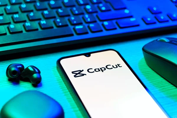Prag, Çek Cumhuriyeti - 08 12 2025: CapCut logosunu gösteren klavyesi ve cep telefonu olan bir masanın yan görüntüsü. CapCut video düzenleme ve oluşturma için bir platformdur.