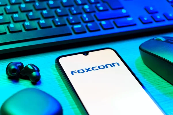 Prag, Çek Cumhuriyeti - 08 12 2025: Foxconn logosunu gösteren klavyesi ve cep telefonu olan bir masanın yan görüntüsü. Foxconn elektronik ve parça üreten bir şirket..