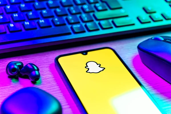 Prague, Czechia - 08 12 2025: A side view of a desk with a keyboard and a mobile phone displaying the Snapchat logo. Snapchat is an app for sending photos, videos, and temporary messages.