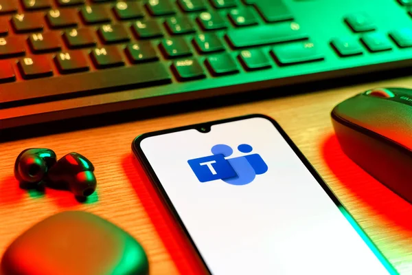Prague, Czechia - 08 12 2025: A side view of a desk with a keyboard and a mobile phone displaying the Teams logo. Teams is a platform for team collaboration, meetings, and communication.