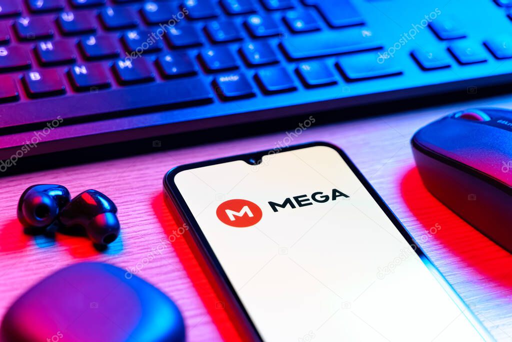 Prague, Czechia - 08 12 2025: A side view of a desk with a keyboard and a mobile phone displaying the Mega logo. Mega is a platform for cloud storage with encrypted file sharing.