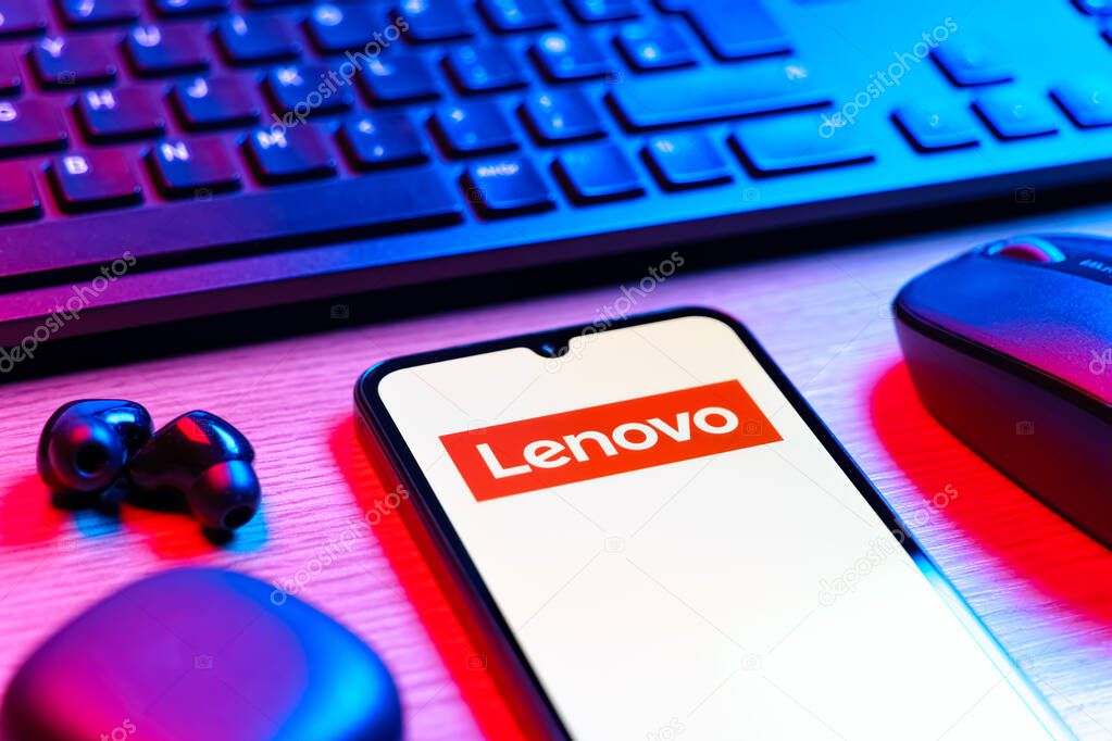 Prague, Czechia - 08 12 2025: A side view of a desk with a keyboard and a mobile phone displaying the Lenovo logo. Lenovo is a technology company producing computers and electronics.
