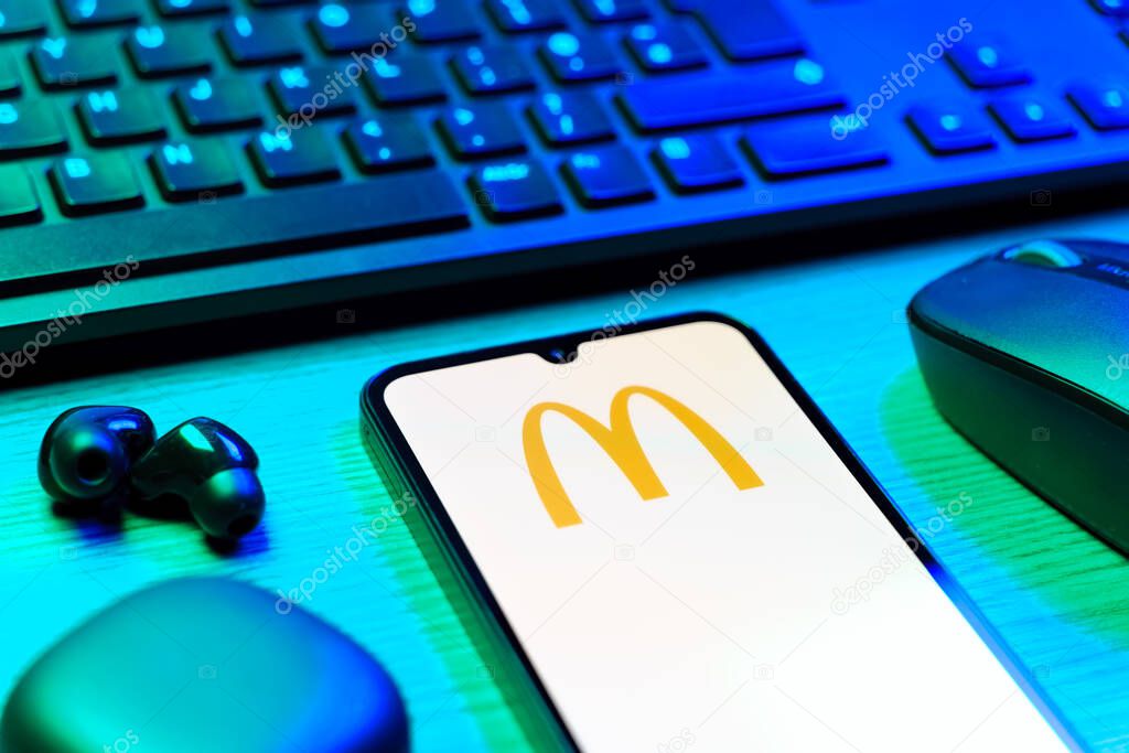 Prague, Czechia - 08 12 2025: A side view of a desk with a keyboard and a mobile phone displaying the McDonalds logo. McDonalds is a fast-food chain serving burgers, fries, and more.