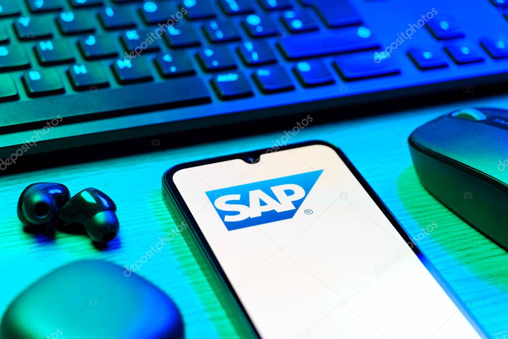 Prague, Czechia - 08 12 2025: A side view of a desk with a keyboard and a mobile phone displaying the SAP logo. SAP is a software company providing enterprise applications and solutions.