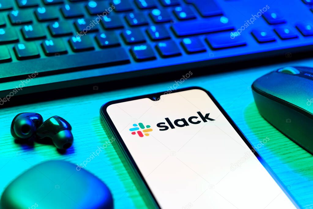 Prague, Czechia - 08 12 2025: A side view of a desk with a keyboard and a mobile phone displaying the Slack logo. Slack is a platform for team messaging and workplace communication.