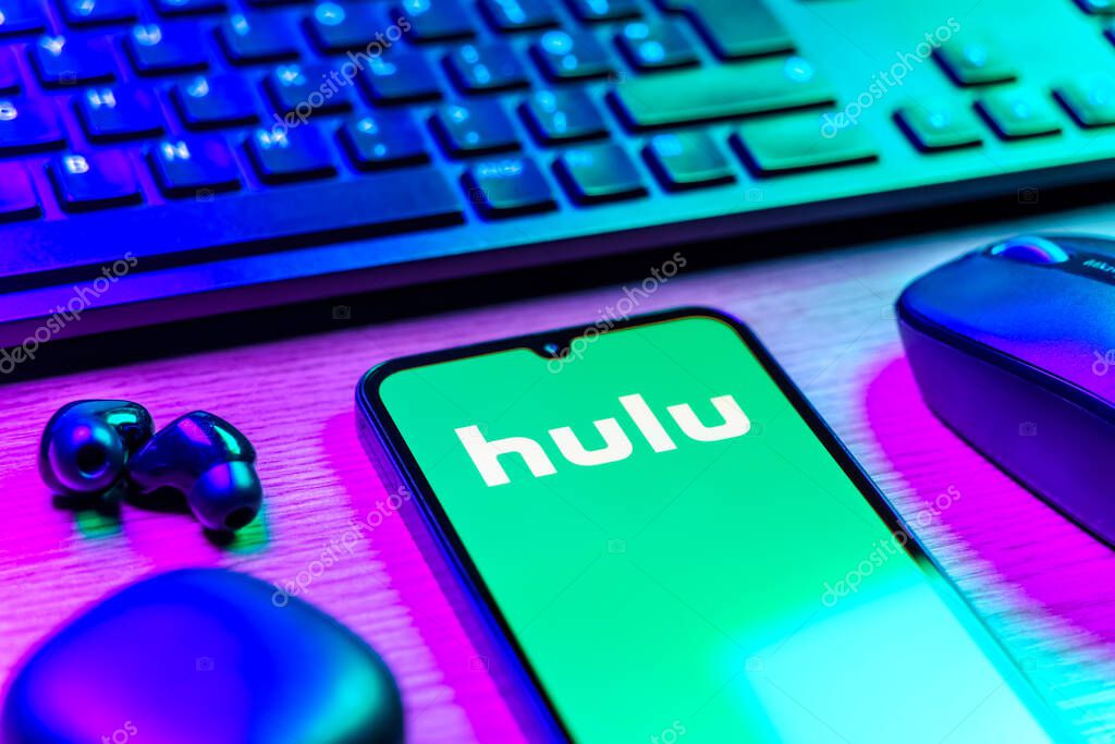 Prague, Czechia - 08 12 2025: A side view of a desk with a keyboard and a mobile phone displaying the Hulu logo. Hulu is a streaming platform for TV shows, movies, and live TV.