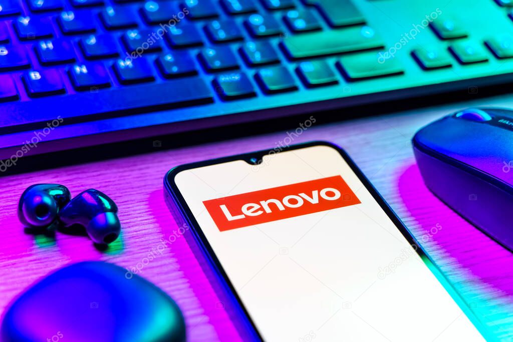 Prague, Czechia - 08 12 2025: A side view of a desk with a keyboard and a mobile phone displaying the Lenovo logo. Lenovo is a technology company producing computers and electronics.