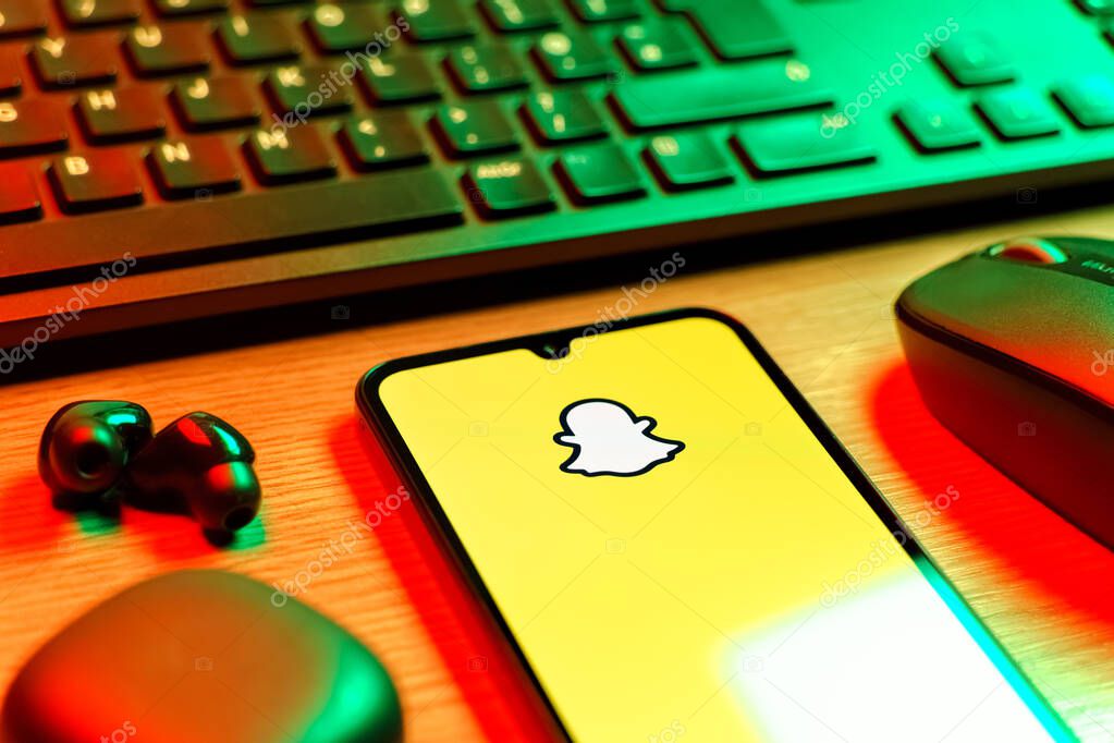 Prague, Czechia - 08 12 2025: A side view of a desk with a keyboard and a mobile phone displaying the Snapchat logo. Snapchat is an app for sending photos, videos, and temporary messages.