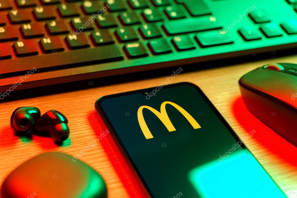 Prague, Czechia - 08 12 2025: A side view of a desk with a keyboard and a mobile phone displaying the McDonalds logo. McDonalds is a fast-food chain serving burgers, fries, and more.