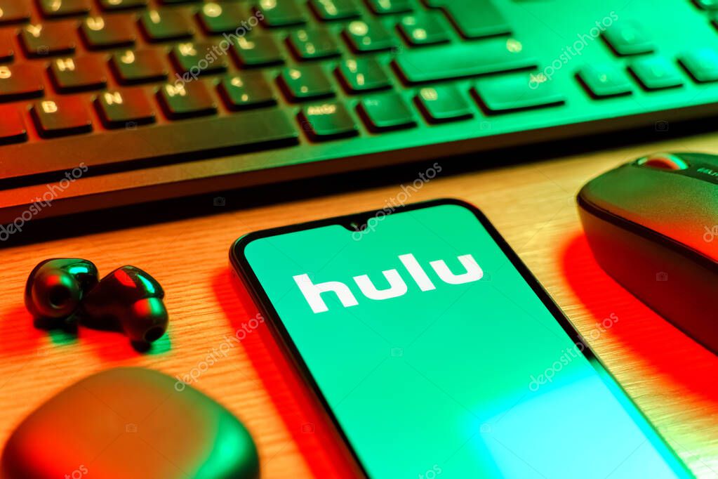 Prague, Czechia - 08 12 2025: A side view of a desk with a keyboard and a mobile phone displaying the Hulu logo. Hulu is a streaming platform for TV shows, movies, and live TV.