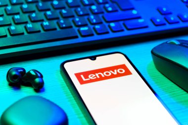 Prag, Çek Cumhuriyeti - 08 12 2025: Lenovo logosunu gösteren klavyesi ve cep telefonu olan bir masanın yan görüntüsü. Lenovo bilgisayar ve elektronik üreten bir teknoloji şirketidir..