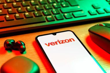 Prag, Çek Cumhuriyeti - 08 12 2025: Verizon logosunu gösteren klavyeli ve cep telefonlu bir masanın yan görüntüsü. Verizon, kablosuz ve geniş bant hizmetleri sağlayan bir telekom şirketidir..